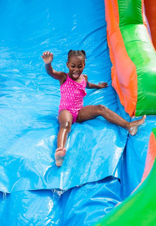 Little girl playing on an inflatable bounce house water slide