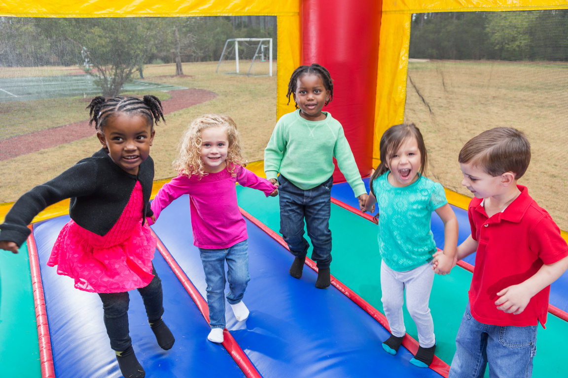 Multi-ethnic group of children jumping in bounce house